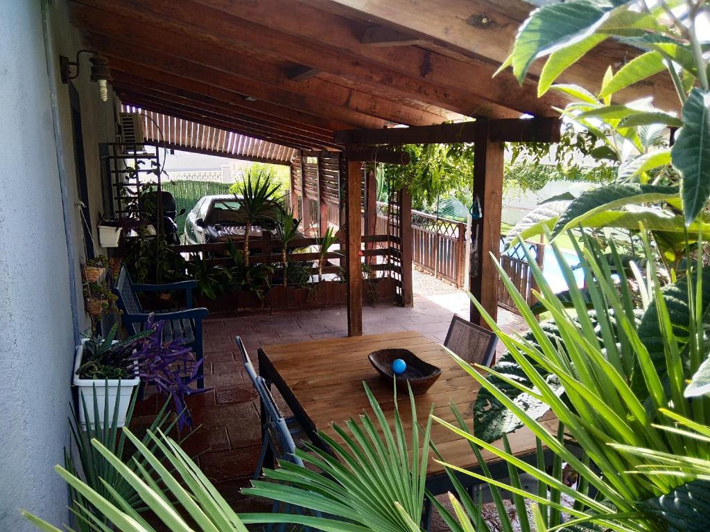 einen Holztisch und Stühle auf einer Terrasse mit Pflanzen in der Unterkunft 4 bedrooms villa with private pool enclosed garden and wifi at Bellvei 6 km away from the beach in Bellvei del Penedes