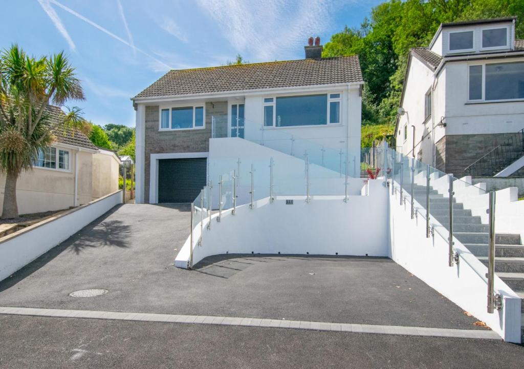 a house with a white fence and a driveway at Crows Nest in Brixham