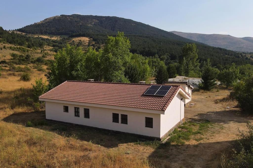 una pequeña casa blanca con paneles solares en el techo en LA MINA Alojamiento en plena naturaleza en Garganta de los Montes