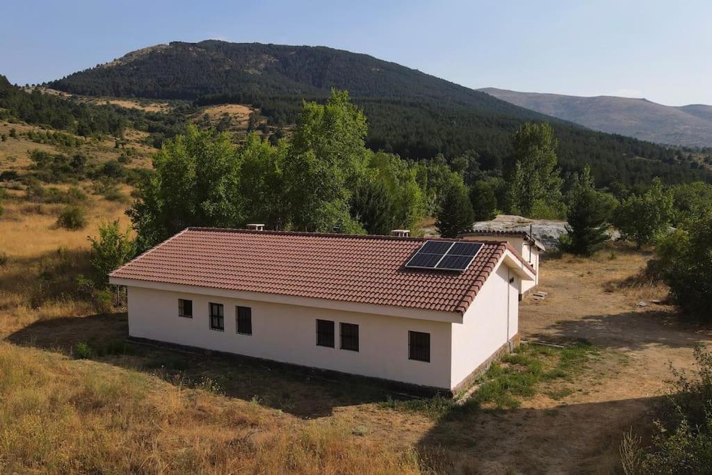 a small white house with solar panels on the roof at LA MINA Alojamiento en plena naturaleza in Garganta de los Montes