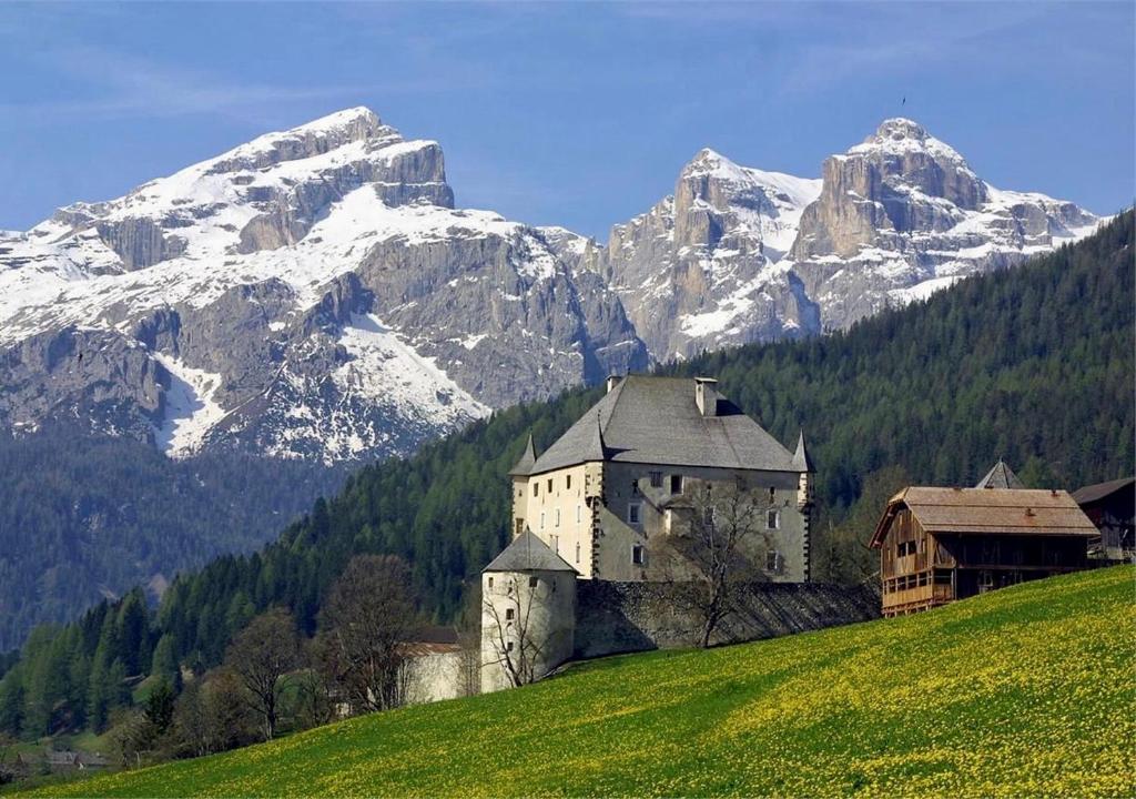 a building on a hill with mountains in the background at Luxury Chalet at the Foot of the Dolomites by the Castle in La Villa