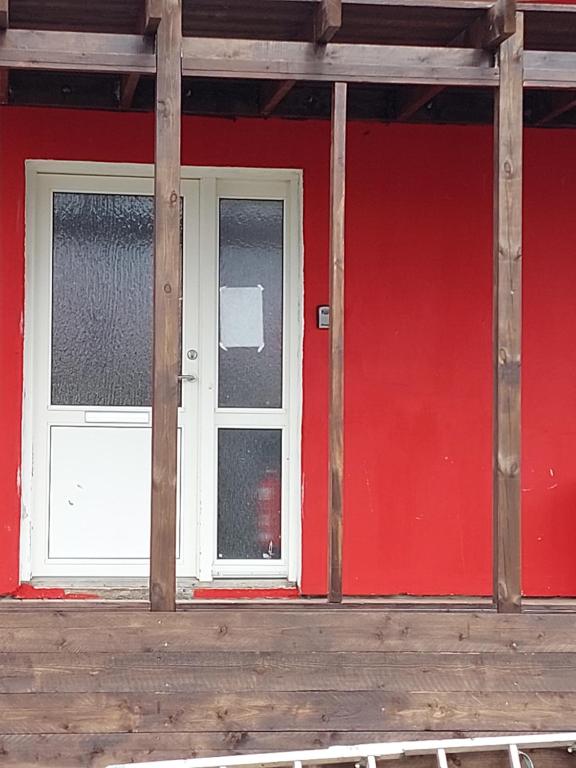 ein rotes Gebäude mit zwei Fenstern und einer roten Wand in der Unterkunft The red house near the sea in Njarðvík
