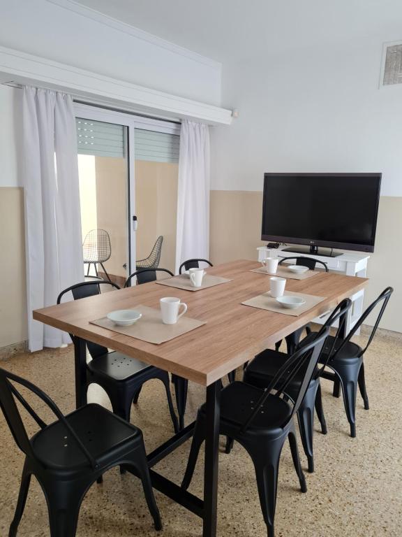 a wooden table with black chairs and a television at BELGRANO HOME. ALQUILER TEMPORARIO EN SAN FRANCISCO in San Francisco