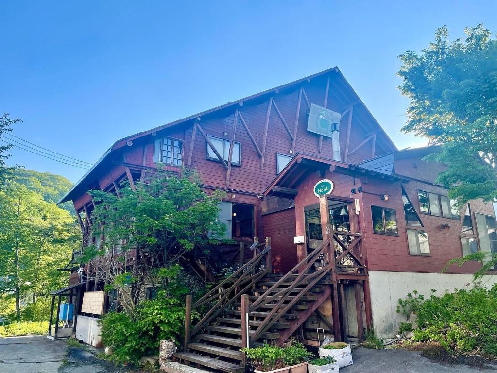 湯沢町にあるHeidi Guest House の木製の階段が目の前にある大きな木造家屋