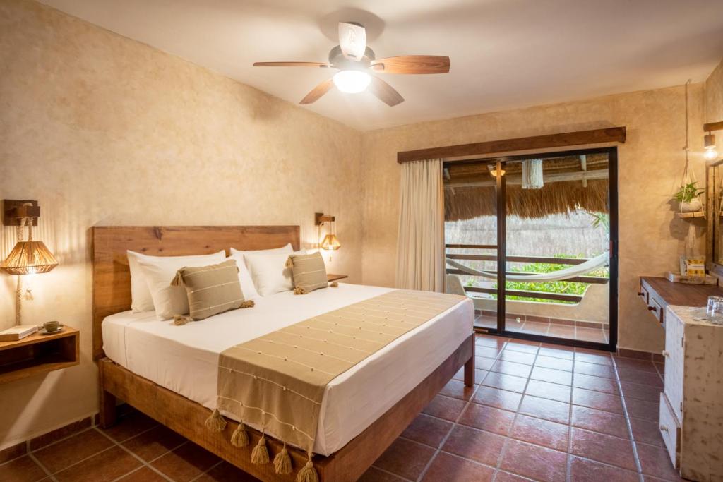 a bedroom with a bed with a ceiling fan and a window at Hotel Colibri Beach in Playa del Carmen