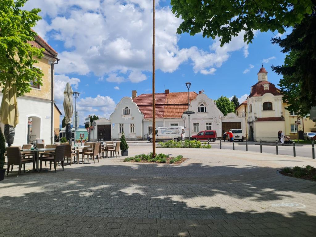 una plaza de la ciudad con mesas, sillas y edificios en Apartmány Modrý deň, en Bojnice