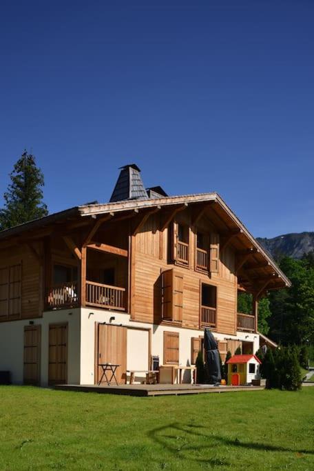 une grande maison en bois dans un champ d'herbe dans l'établissement Appartement dans chalet de luxe Megève, à Megève