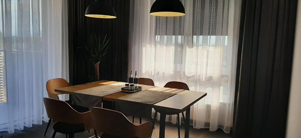 uma mesa de jantar e cadeiras num quarto com cortinas em Belweder LOFT em Nysa