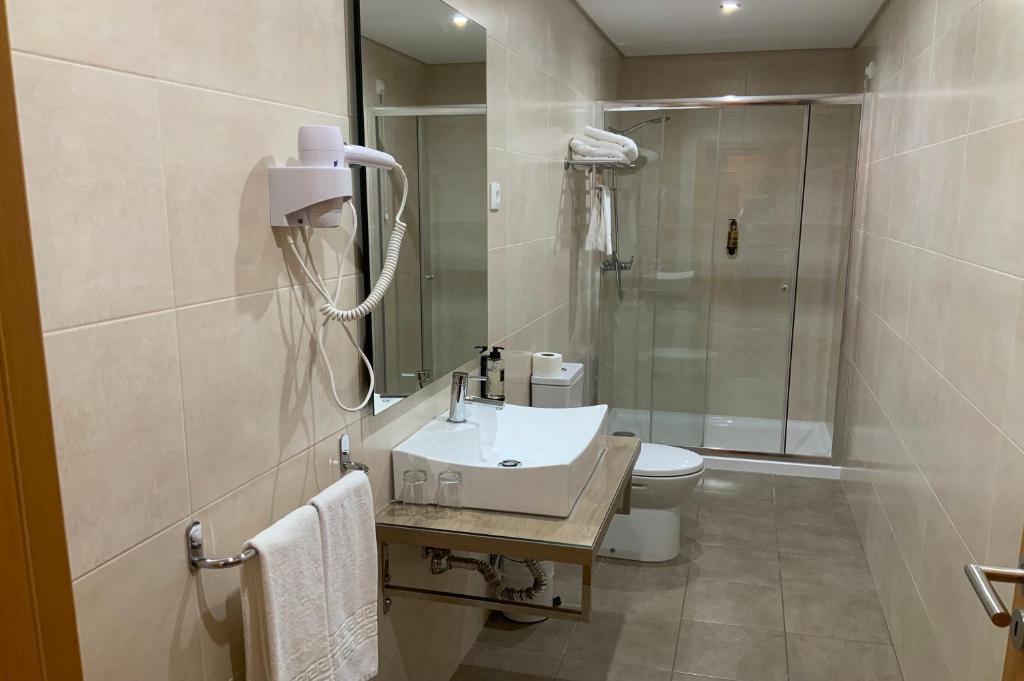 a bathroom with a sink and a toilet and a shower at Hotel Mare in Nazaré