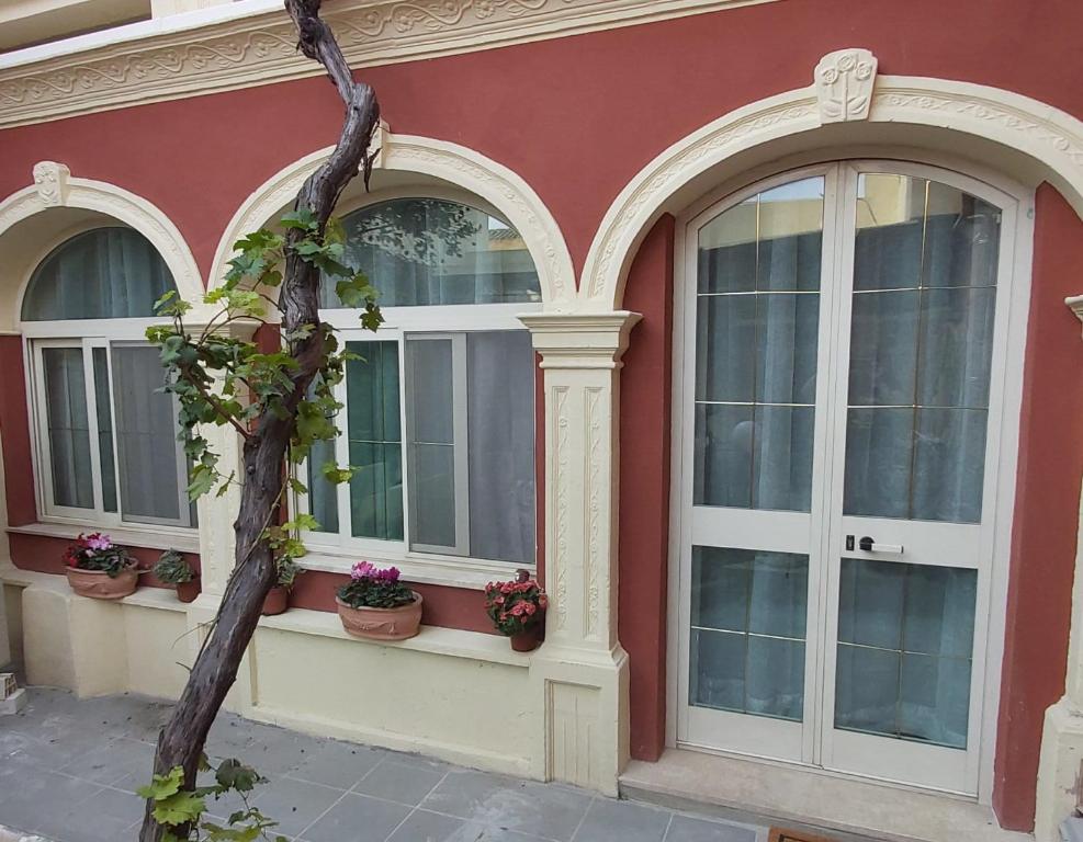 un edificio rosso con tre finestre e piante in vaso di I TRE ARCHI FIORITI a Quartucciu