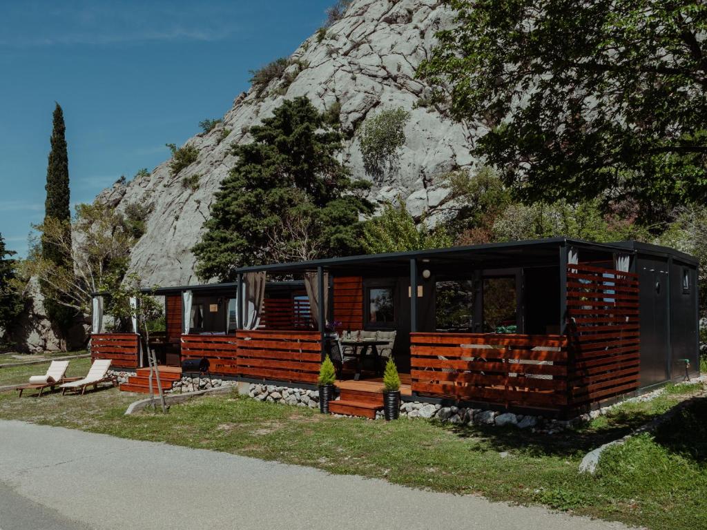 a black cabin with a mountain in the background at Mobile home Aurora in Sveti Juraj