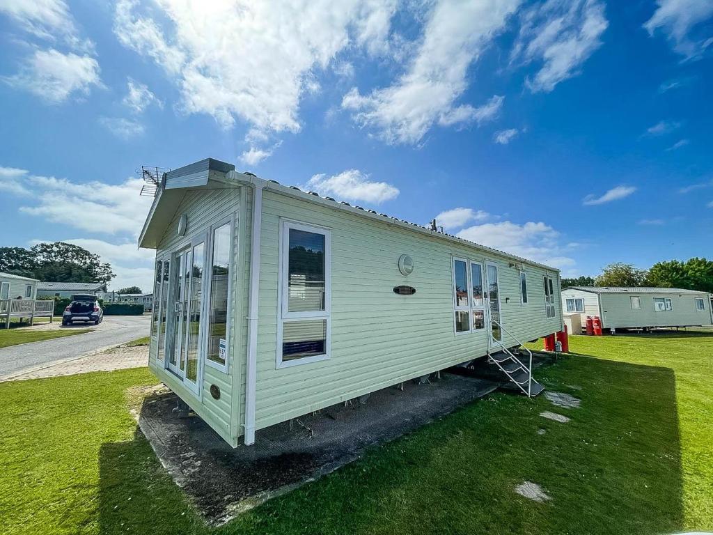 a small white tiny house on a grass field at Beautiful Caravan At Highfield Grange Holiday Park In Essex Ref 26687p in Clacton-on-Sea