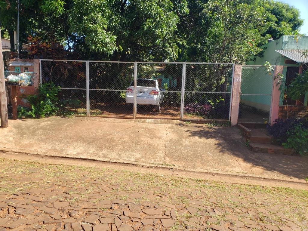 a fence with a car parked in front of a house at Alojamiento El Remanso in Puerto Iguazú