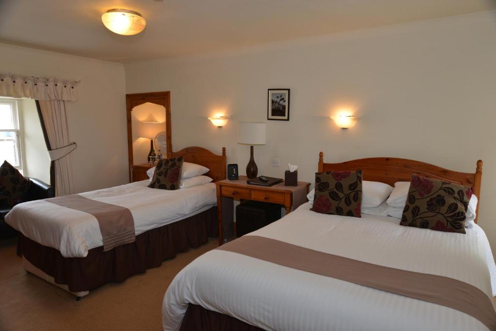 a hotel room with two beds and a table with lamps at The Golf Hotel in Crail