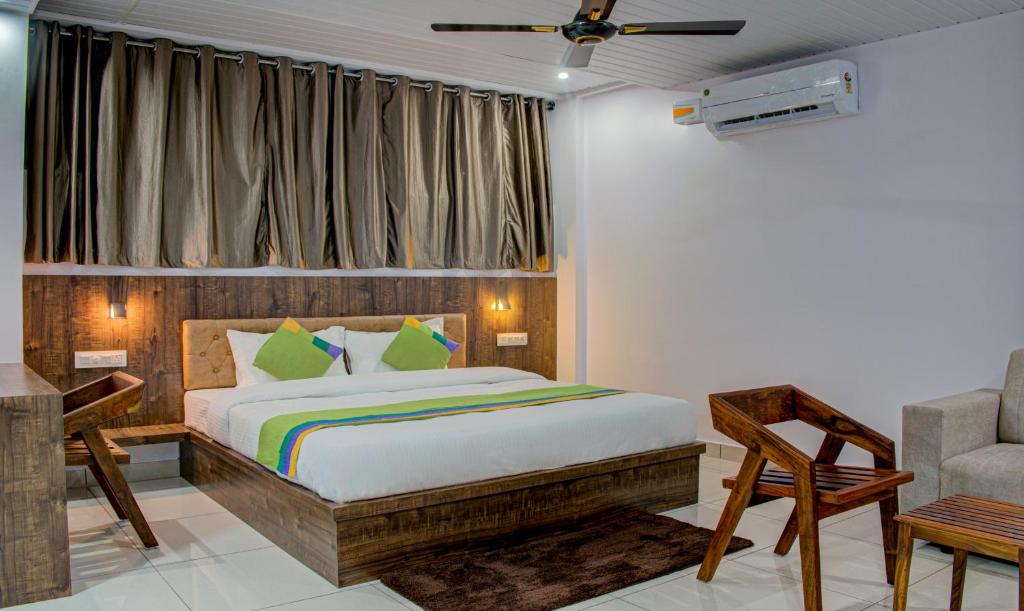 ein Schlafzimmer mit einem Bett, einem Stuhl und einem Sofa in der Unterkunft Treebo Trend Lucent The Homely Stay in Chikmagalur