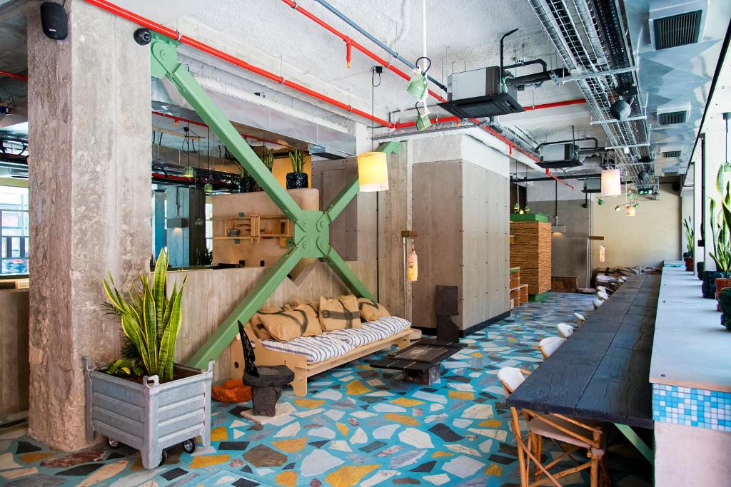 The lobby uses exposed services, colorful mosaic flooring, timber dividers, and informal seating.