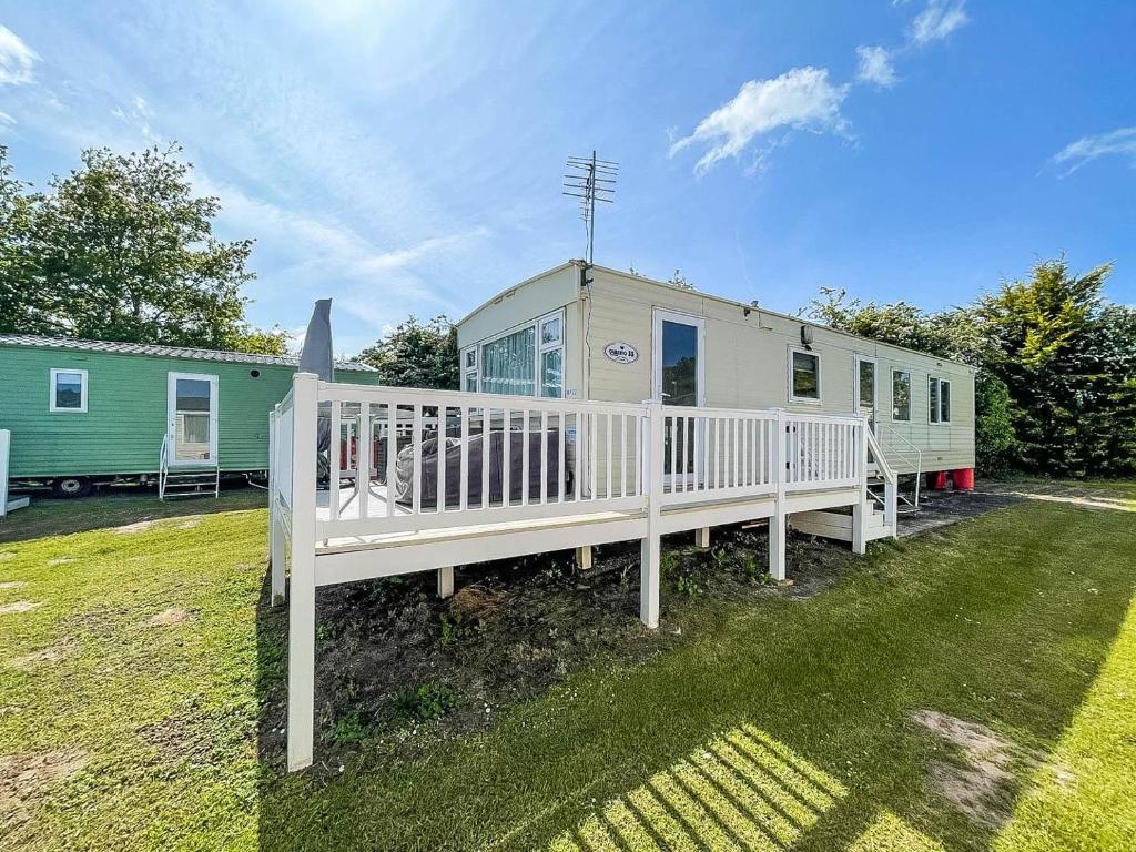 a mobile home with a white deck and a house at 6 Berth Caravan Nearby Great Yarmouth In Norfolk Ref 10022rp in Belton