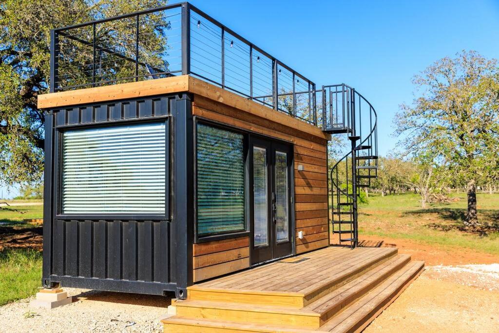 a tiny house with a deck and a railing at New Wilderness Hideout-Cozy Container Home in Fredericksburg