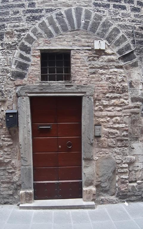 a brick building with a brown door and a window at Civico in Gubbio