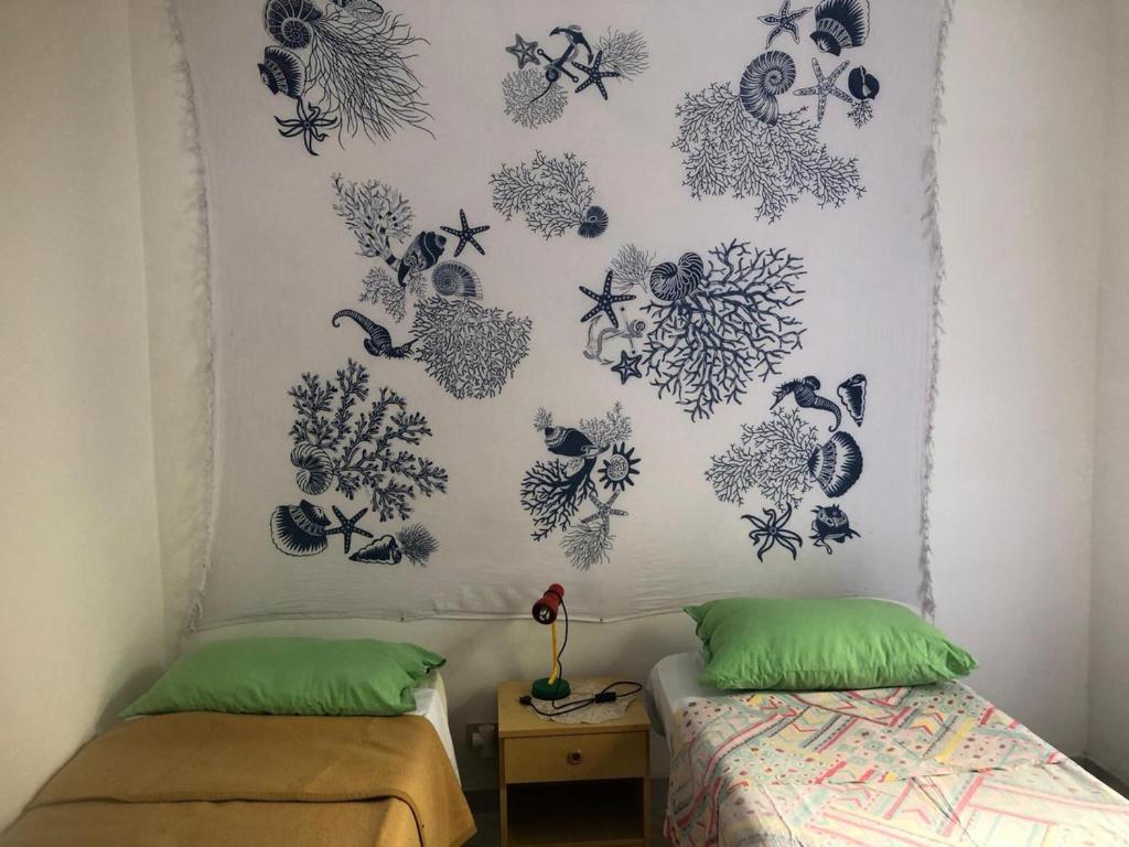 een slaapkamer met 2 bedden en een muur met tekeningen erop bij Casa Icaro in Marinella di Selinunte