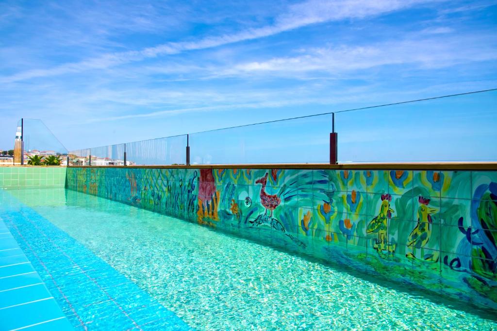 A rooftop-style pool with a bright mural wall and open city surroundings.