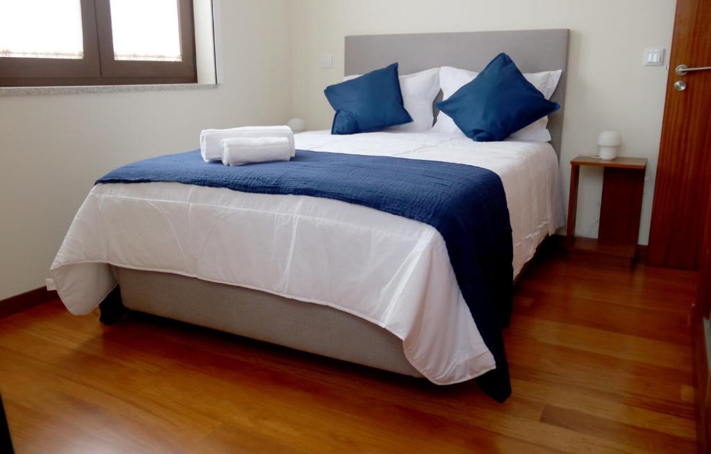 uma cama grande com lençóis azuis e brancos e almofadas azuis em Cabo do Mar Apart.- Sereias Beach em Espinho
