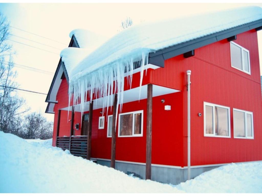 新雪谷的住宿－niseko / Vacation STAY 4376，雪覆盖着的红色房子,上面有 ⁇ 石
