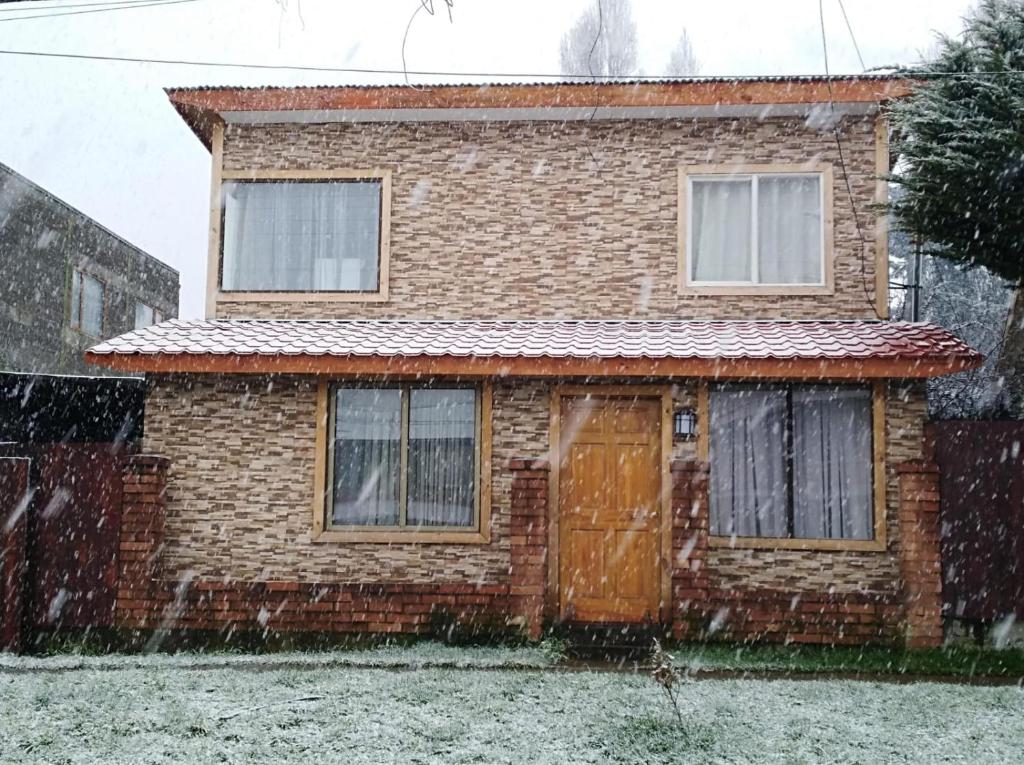 a brick house with a door in the snow at CABAÑAS TRAPAGONIA in Coihaique