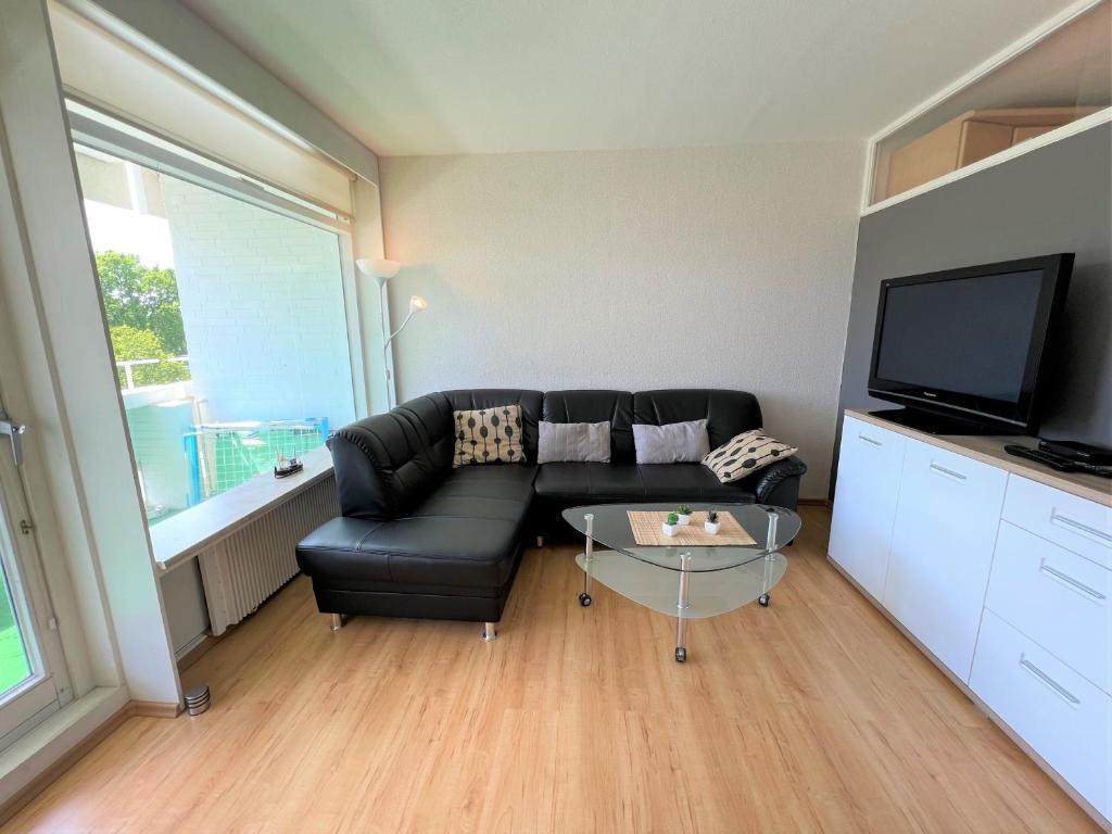 uma sala de estar com um sofá preto e uma televisão em Panoramic App B02-6 em Sierksdorf