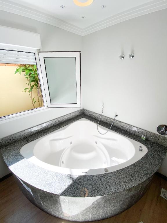 a large bath tub in a room with a window at Hotel Raul's in Gaspar