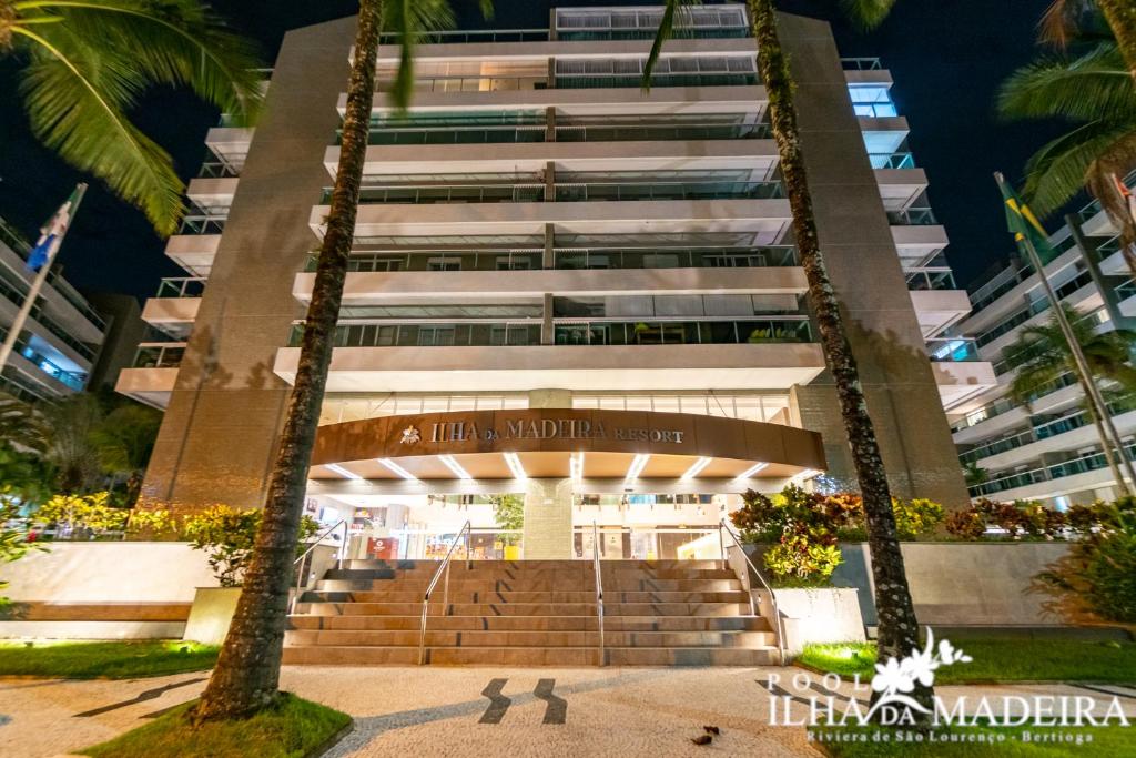 Un edificio con palmeras delante. en Pool Ilha da Madeira Resort, en Riviera de São Lourenço