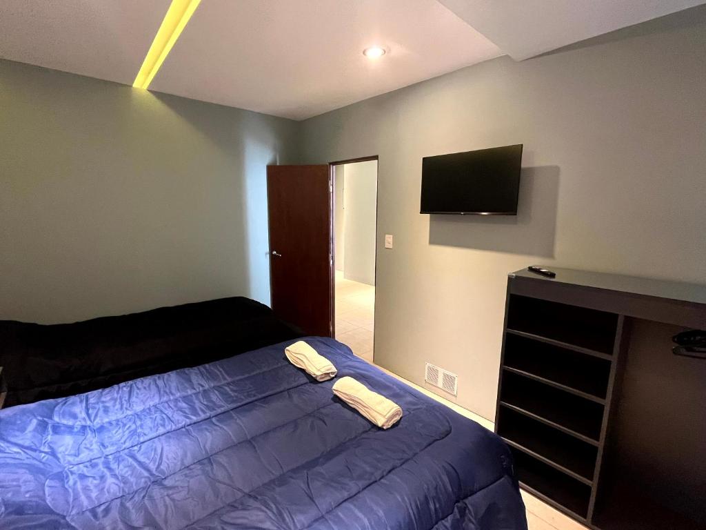 a bedroom with a bed and a flat screen tv at Departamentos Muskuy - Salta Capital in Salta