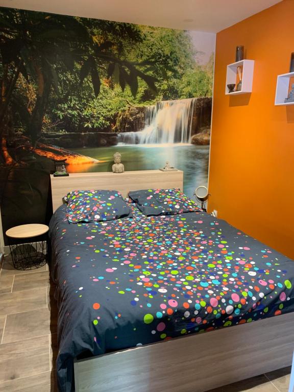 a bedroom with a bed with a waterfall painting on the wall at Dépendance dans le jardin in Franqueville-Saint-Pierre