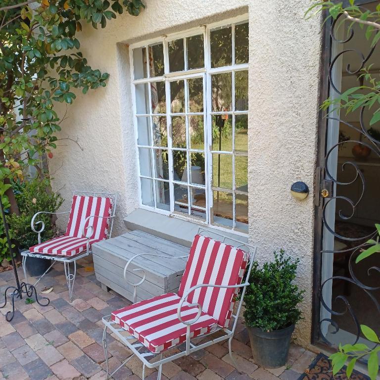two red and white chairs sitting in front of a window at Craighall Park Stylish Garden Studio in Johannesburg