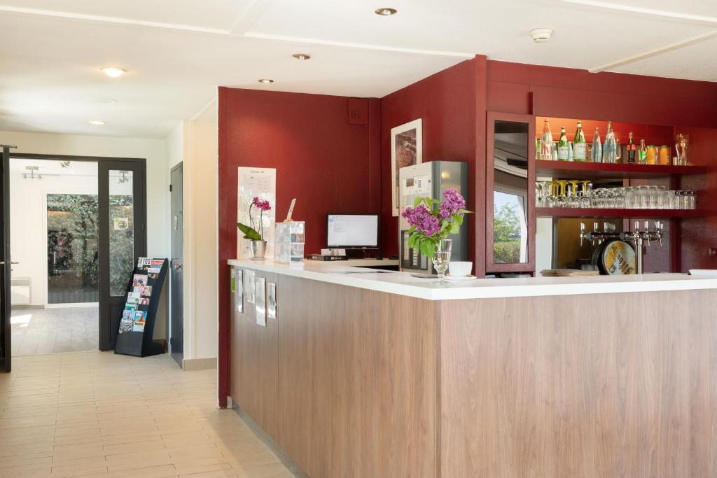 a bar in a restaurant with red walls at Campanile Dole in Dole