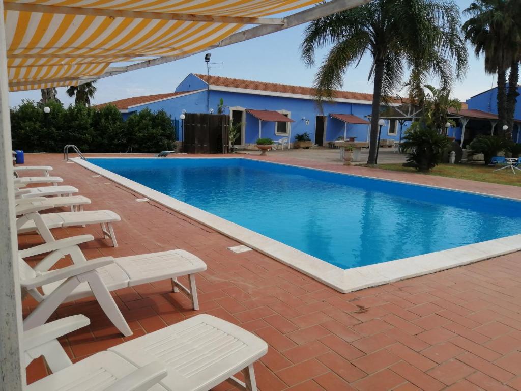 una piscina con sillas blancas y un complejo en Mediresidence Maeggio, en Contrada Maeggio