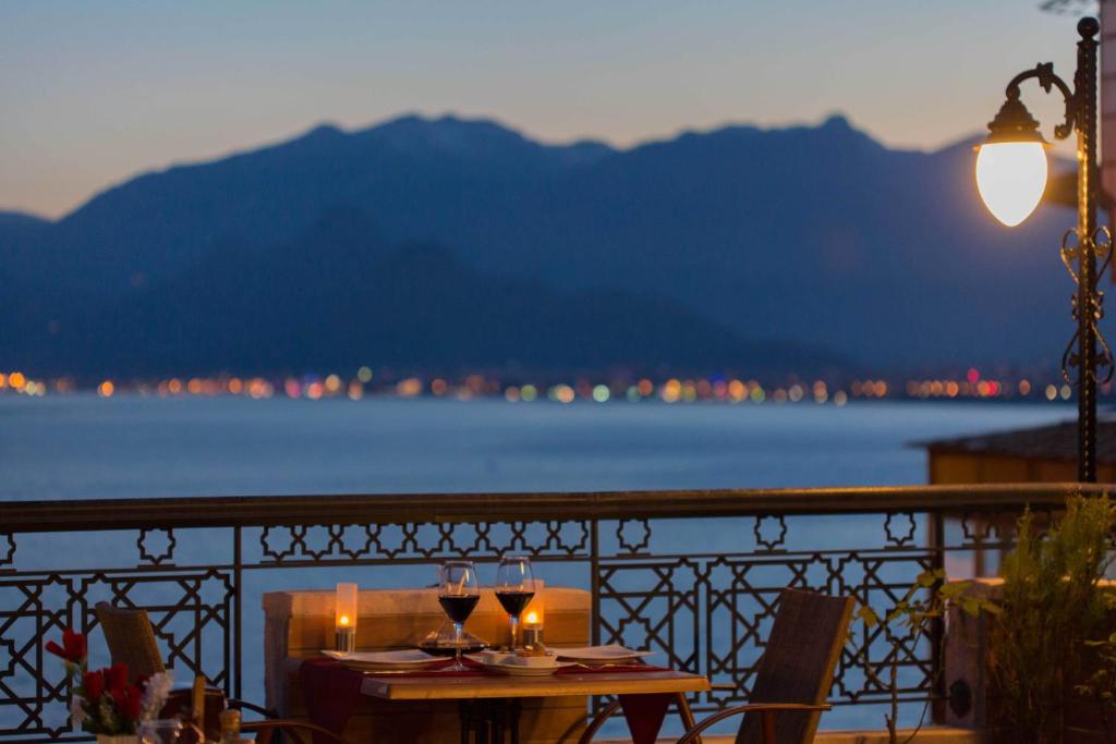 een tafel met wijnglazen op een balkon met uitzicht op het water bij Antalya Inn Hotel in Antalya