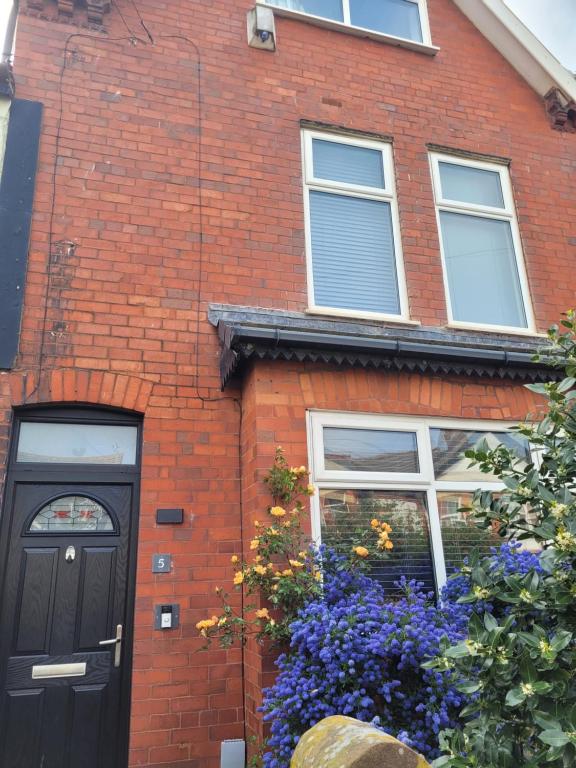 a red brick house with a black door and flowers at Hoylake 2 double bedrooms, continental breakfast included for the 151ist golf open at the Royal Liverpool in Hoylake