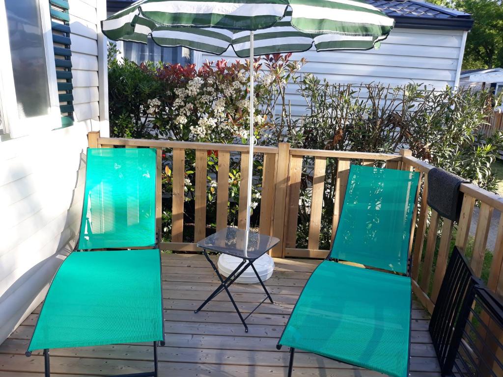 two green chairs and an umbrella on a deck at Mobilhome 6 pers avec Clim in Saint-Georges-de-Didonne