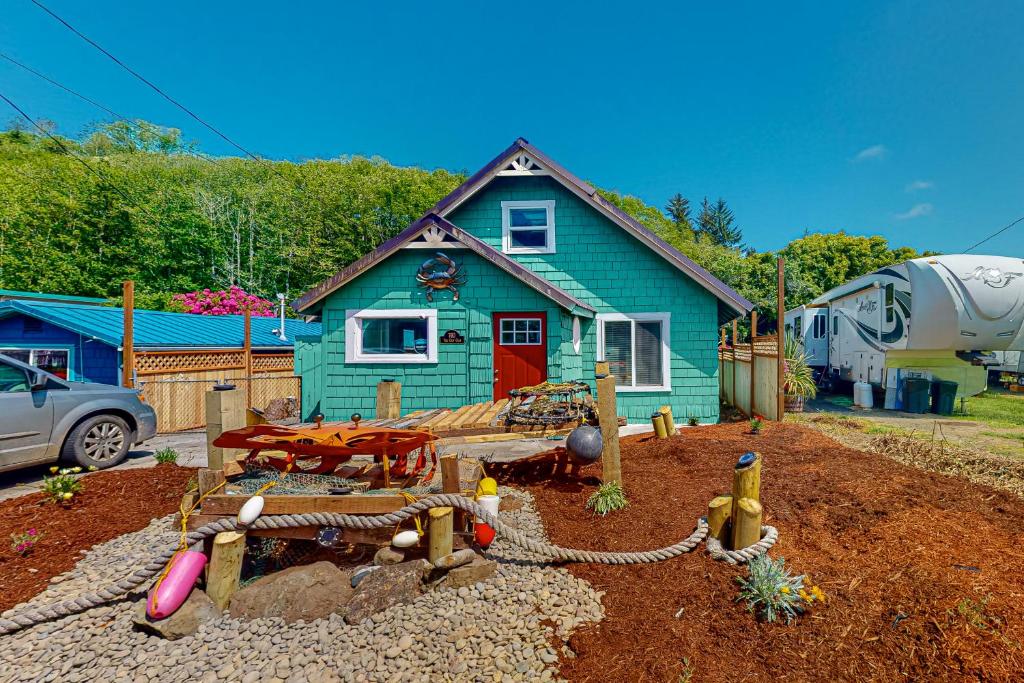 una casa azul con un patio de juegos delante de ella en The Cozy Crab Cottage, en Reedsport