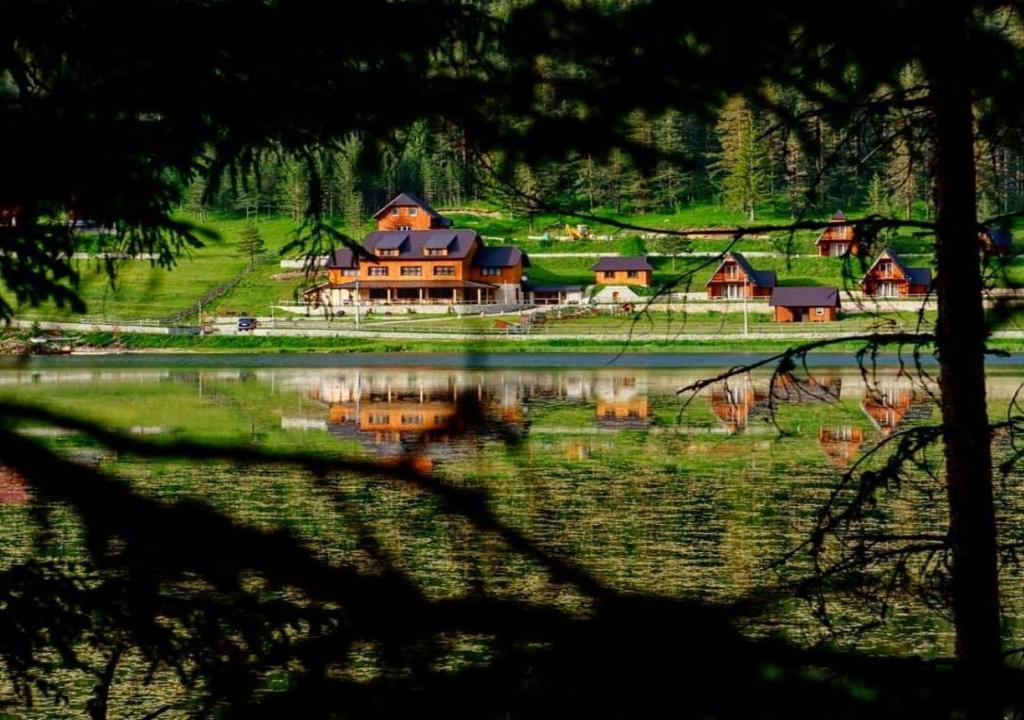 a large house on a hill next to a lake at Etno selo Zminica in Žabljak