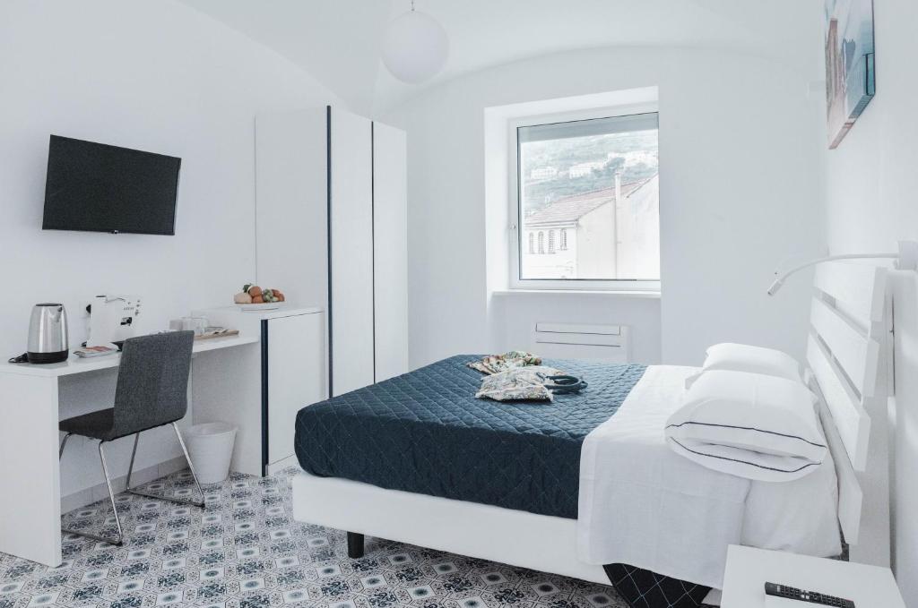 a white bedroom with a bed and a desk at A Gradillo holiday rooms in Ravello