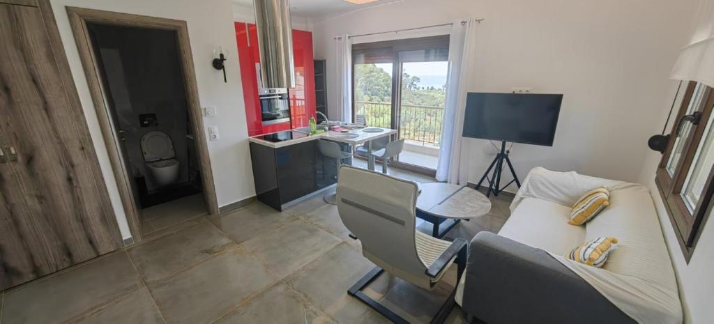 a living room with a couch and a desk and a television at Theasis 2 in Neos Marmaras