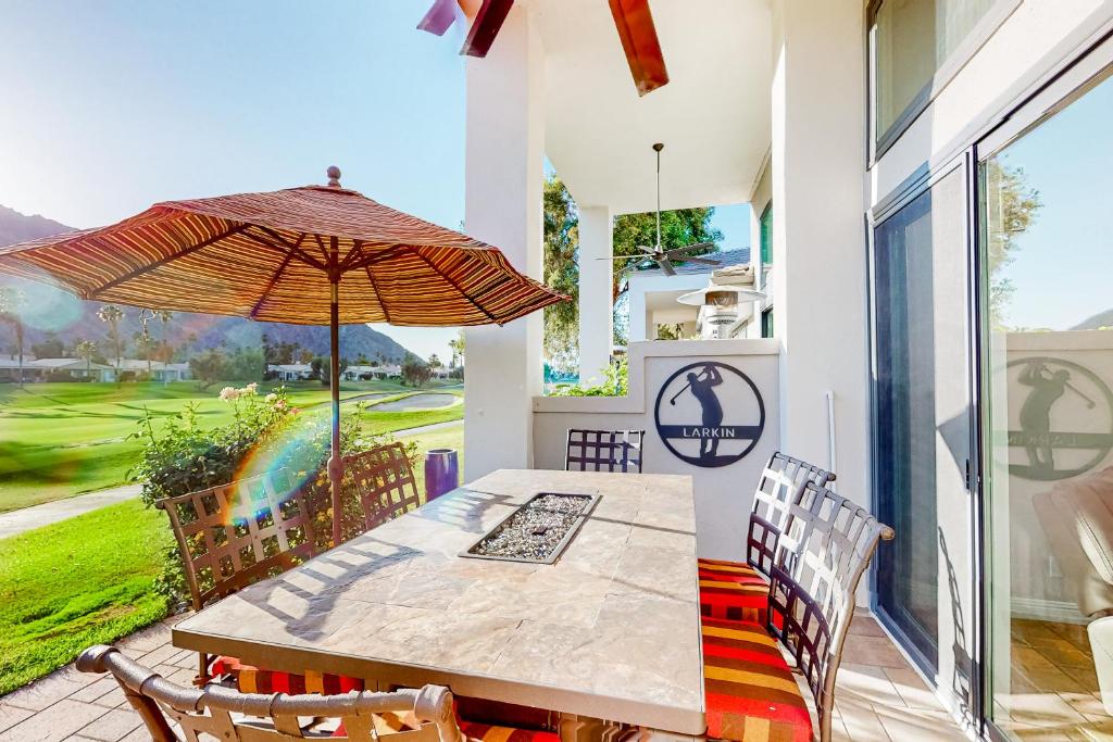 - une salle à manger avec une table et un parasol dans l'établissement Palm Retreat, à La Quinta