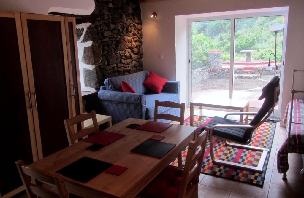 a dining room with a table and chairs and a couch at Palheiro da Assomada in Faja Grande