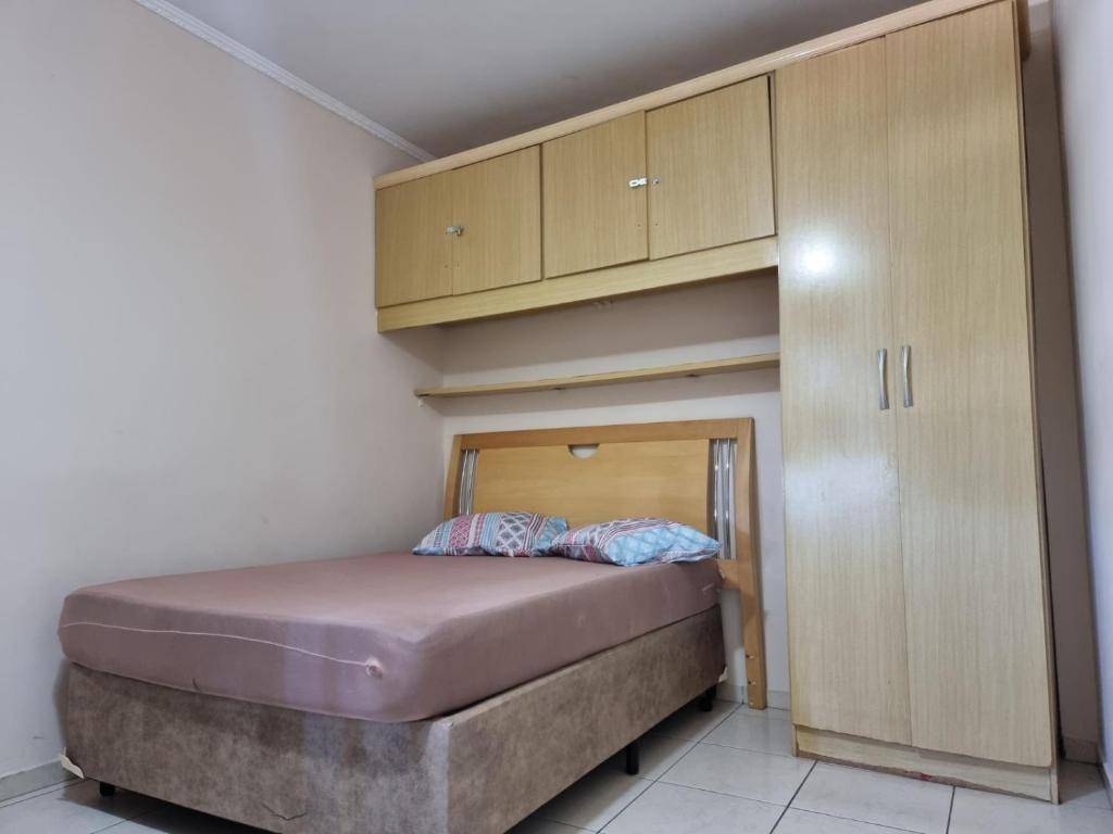 a small bed in a room with wooden cabinets at Pé na Areia in Santos