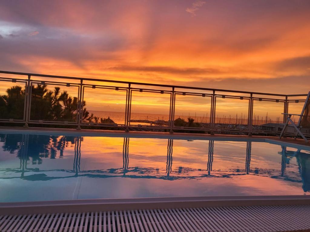a swimming pool with a sunset in the background at Hotel Ariella in Milano Marittima