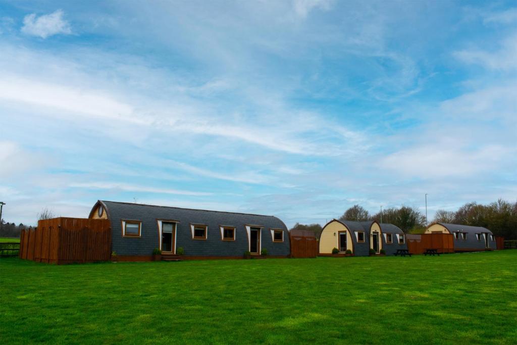 a group of houses in a field with a green field at Dragons Den in Norwich