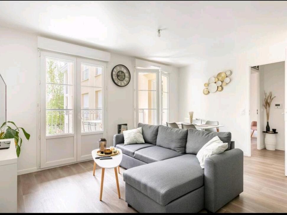 uma sala de estar com um sofá cinzento e uma mesa em Appartement Cosy à 8 min Disney 20 min Paris em Montévrain