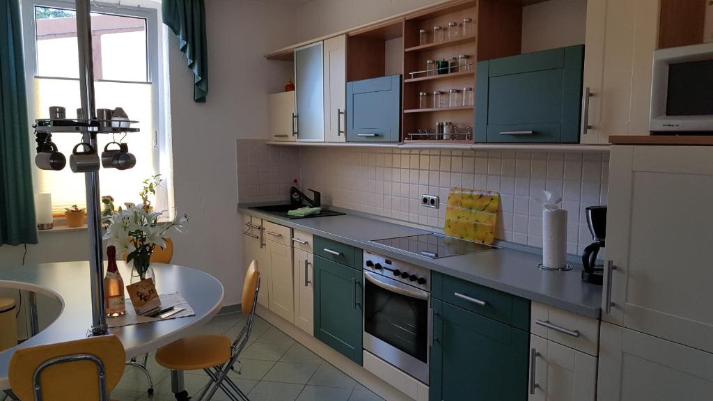 een keuken met groene kasten en een tafel bij ALACARD Ferienwohnungen Höffgen Thale Harz in Thale